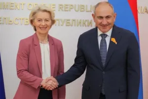 European Commission President Ursula von der Leyen and Armenian Prime Minister Nikol Pashinyan shaking hands and smiling in front of an official government backdrop.